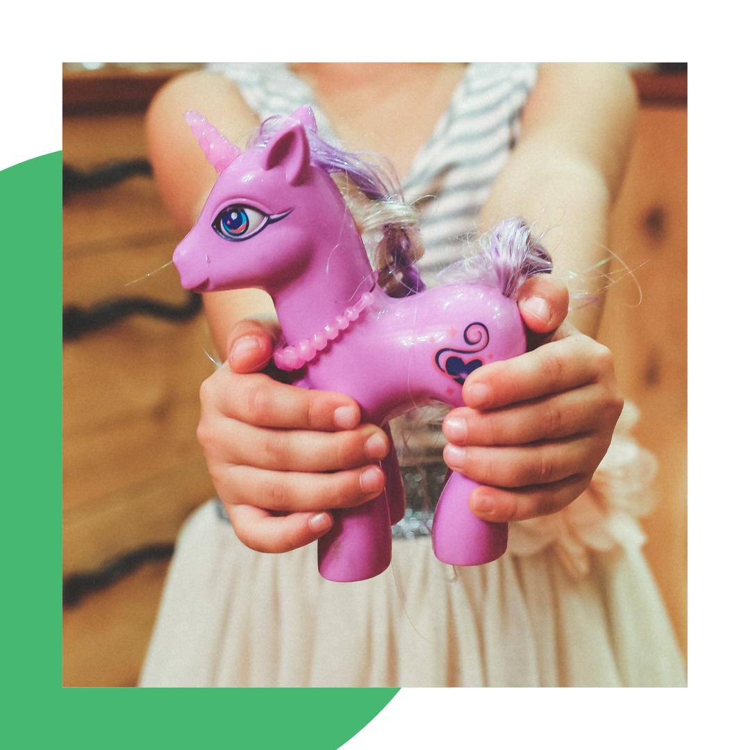 A child holding out a pink unicorn toy ready to donate to charity for Christmas.