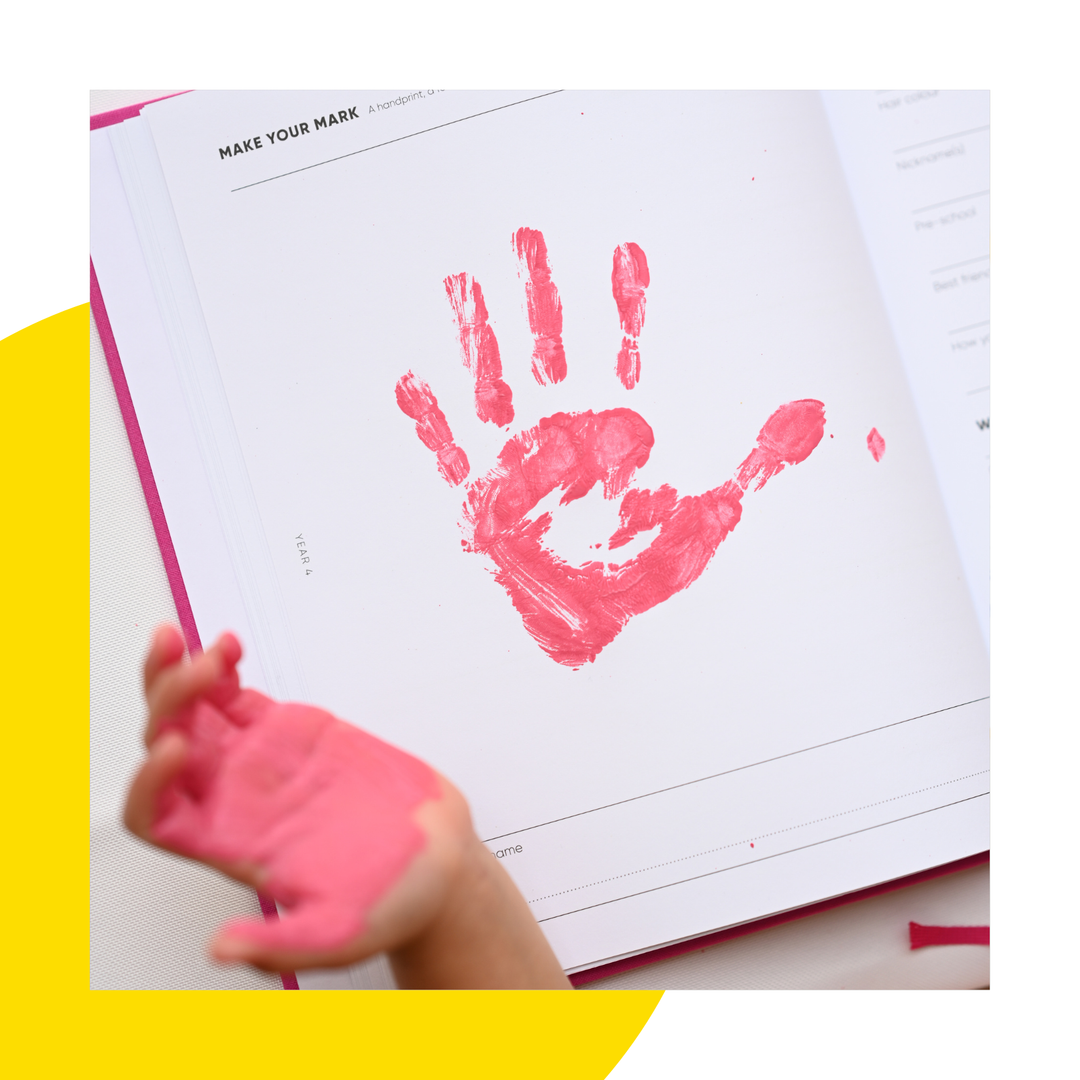 A child doing a handprint in their copy of The Book of You