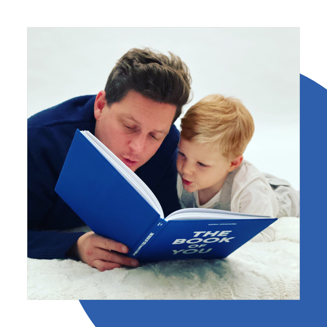 Father and child enjoying The Book of You memory journal in blue
