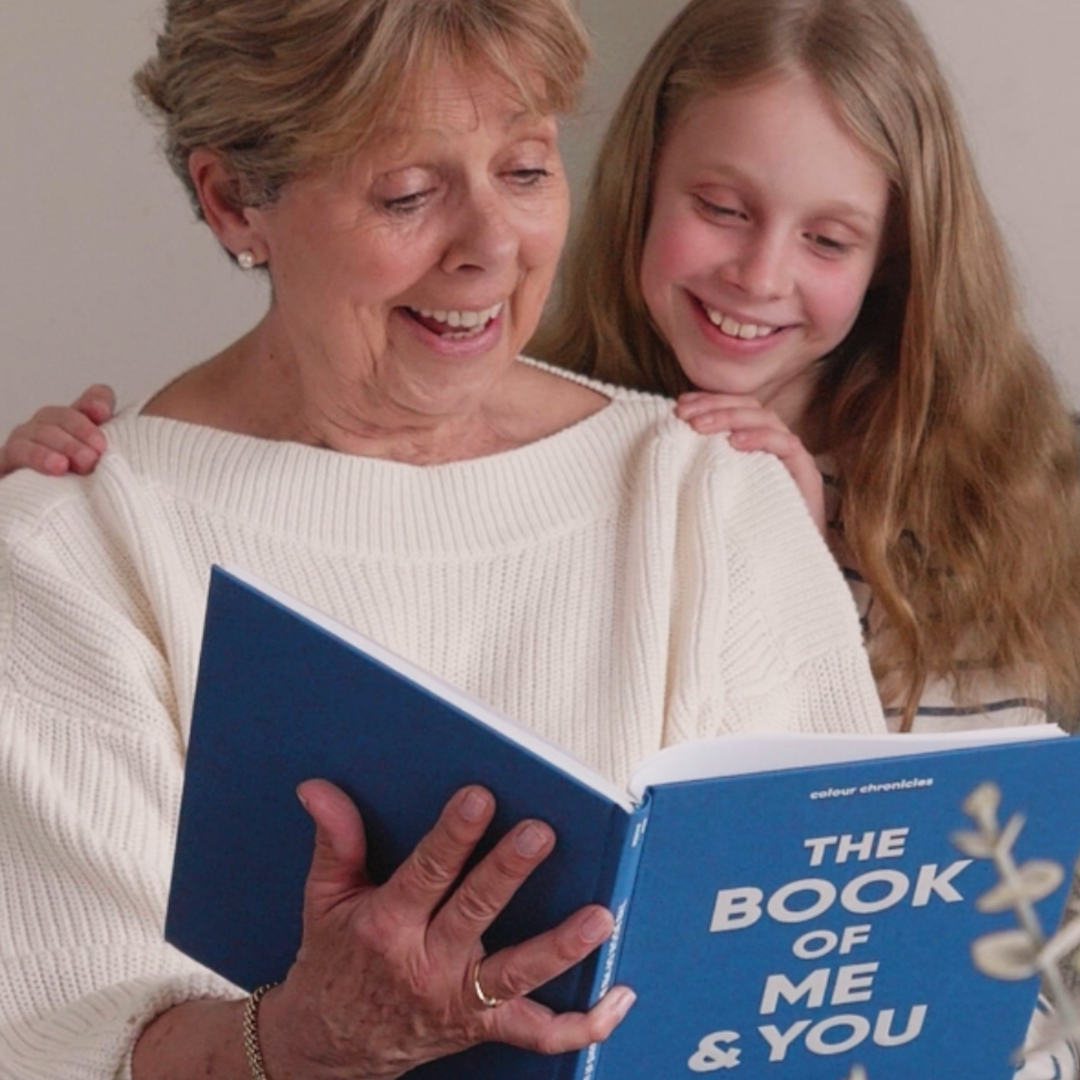 A grandmother and granddaughter enjoying their shared memory journal The Book of Me and You in blue