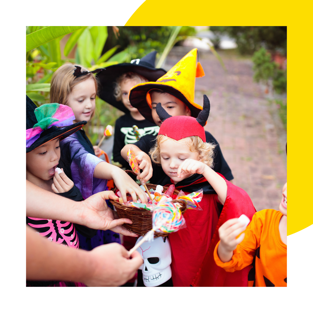Children dressed up for Halloween taking sweets from a bucket. 