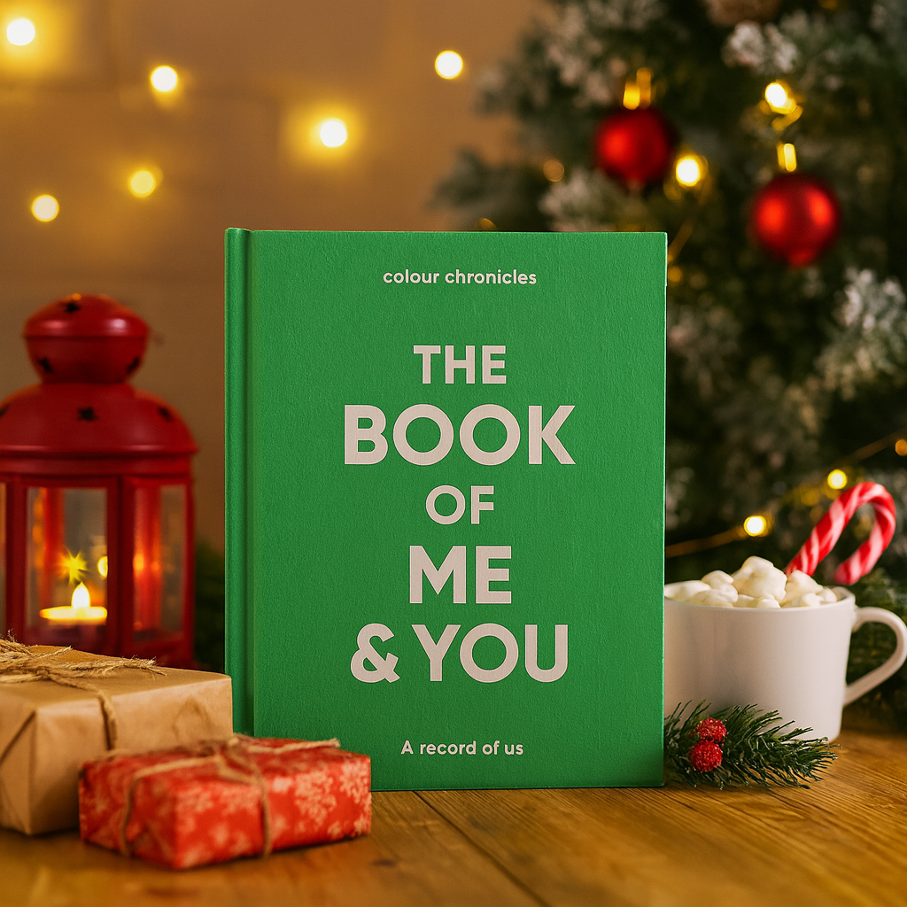 Grandparent memory journal shown in green in front of a Christmas tree and some wrapped gifts.