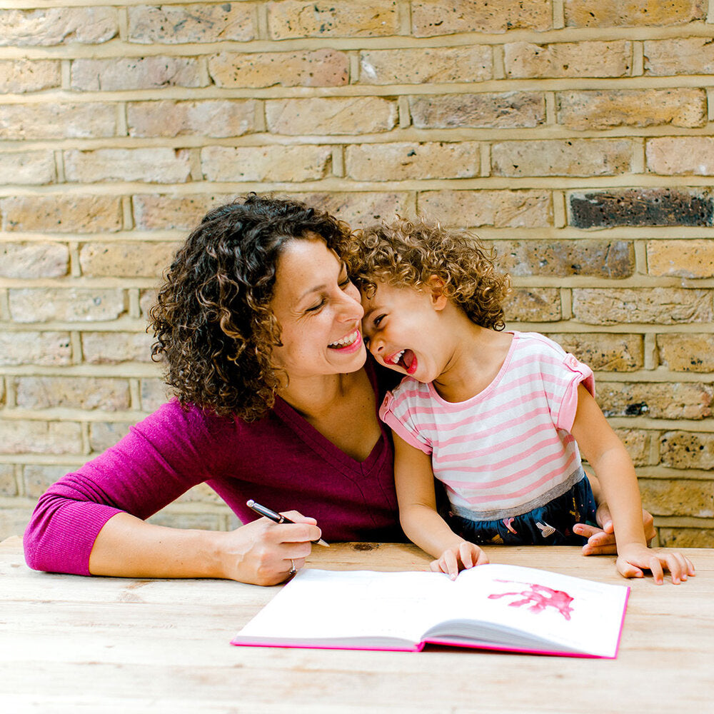 Mother with young child using childhood memory scrapbook with handprints